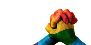 Two hands painted in colours of the rainbow held up against a white background